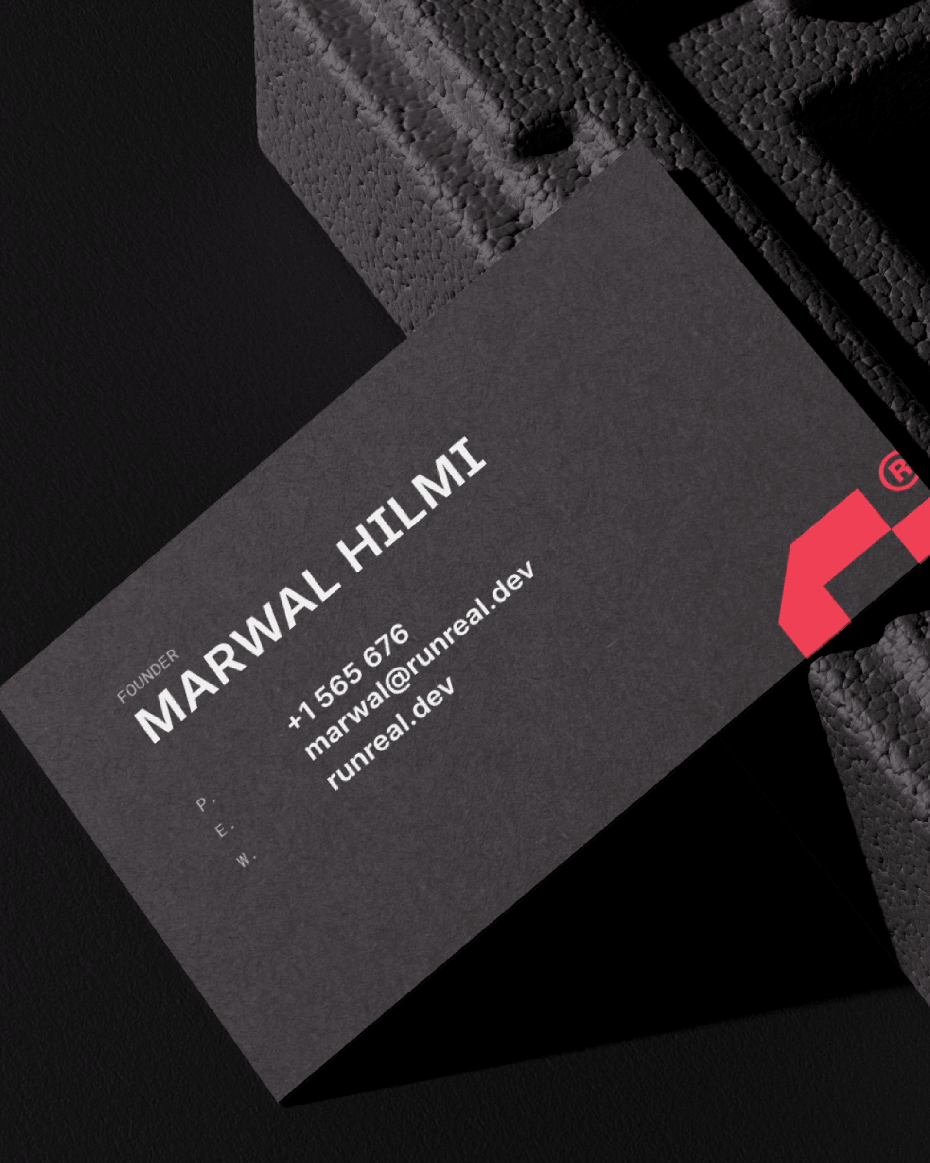 Close-up of a dark Runreal business card for founder Marwal Hilmi with bold white typography and a red geometric logo, designed by Kundo Studio to showcase the tech-forward brand identity and print collateral system.