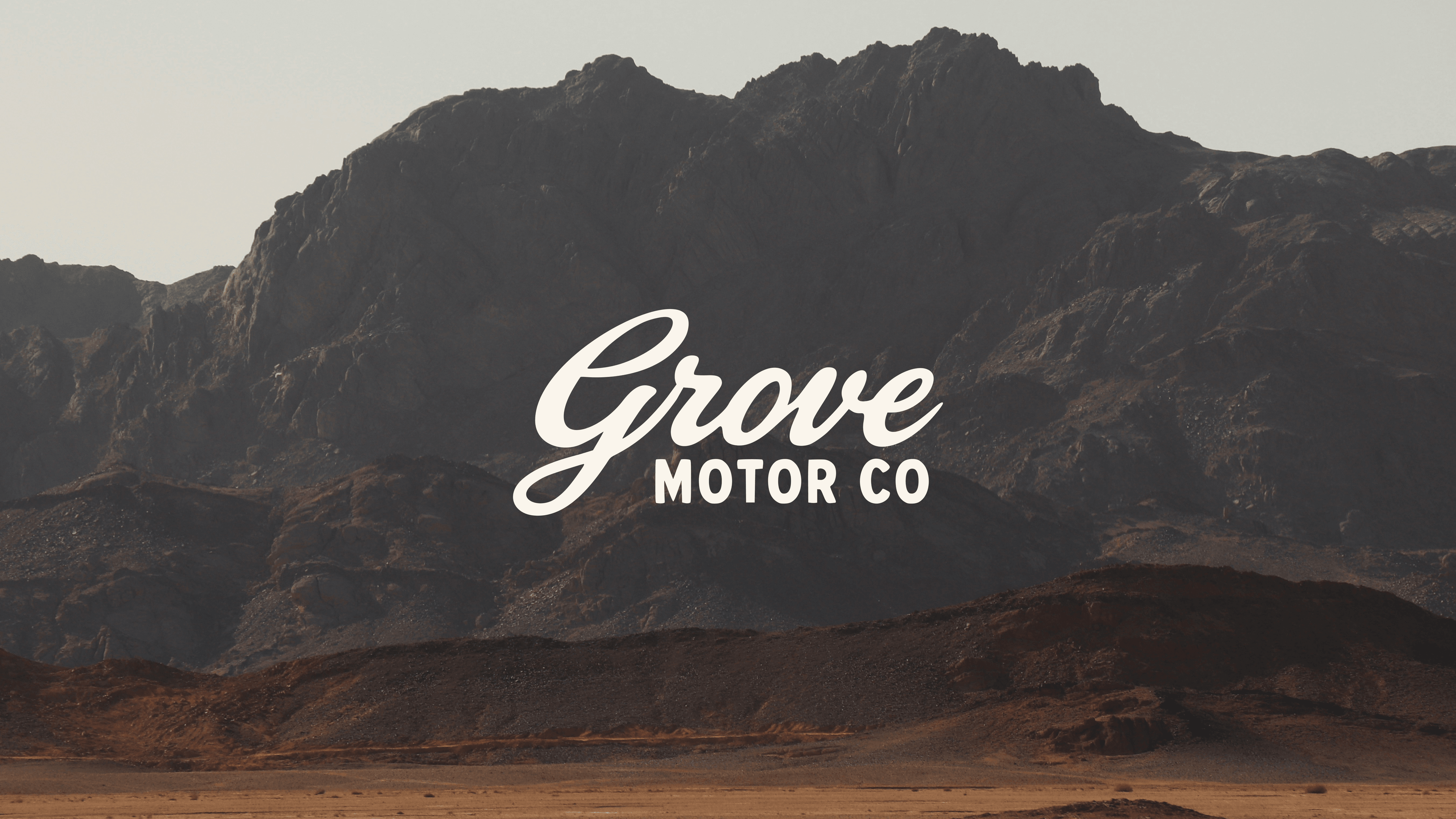 Grove Motor Co wordmark over a rugged mountain landscape.